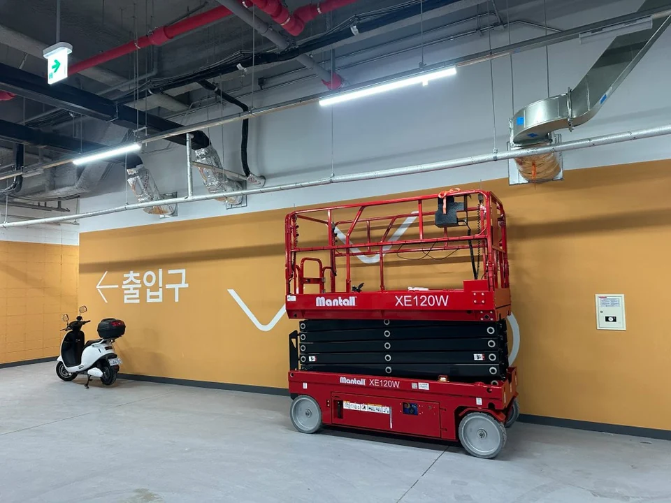 지하주차장 천장 설비 아래 배치된 XE120W 시저리프트